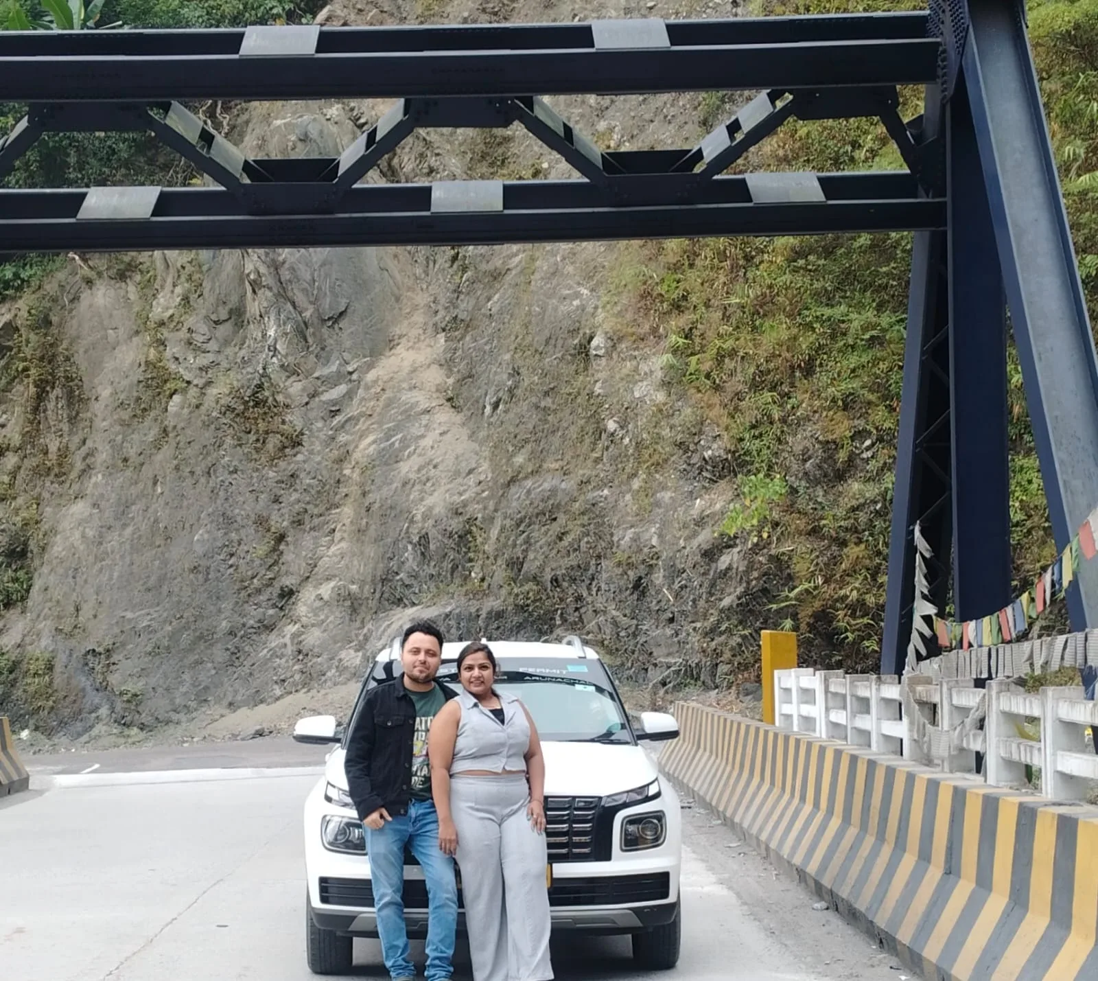 A vehicle paused on a mountain road above a green valley