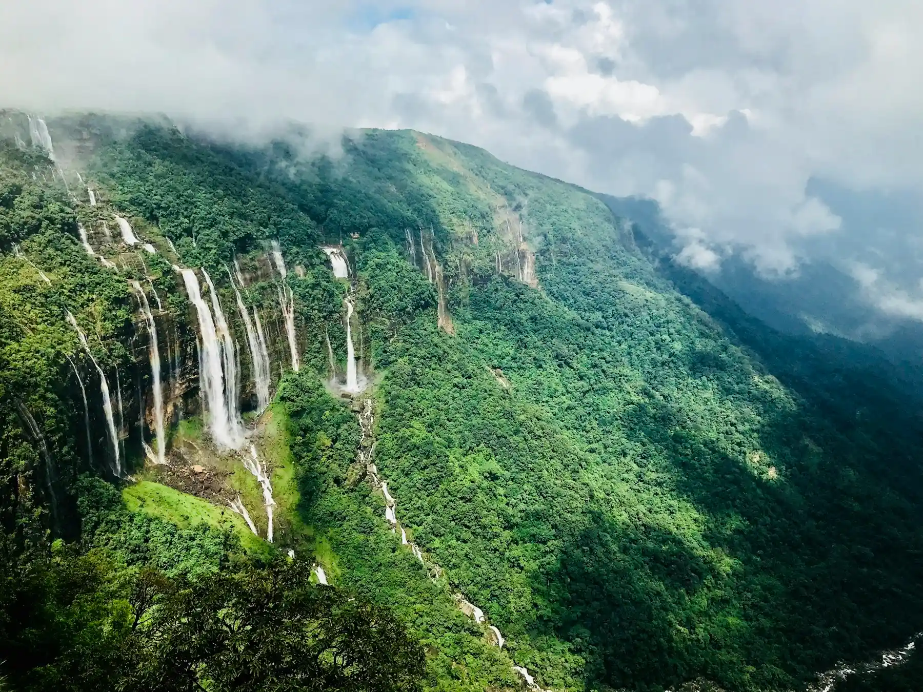 The Seven Sisters Falls spilling over a green Meghalaya escarpment